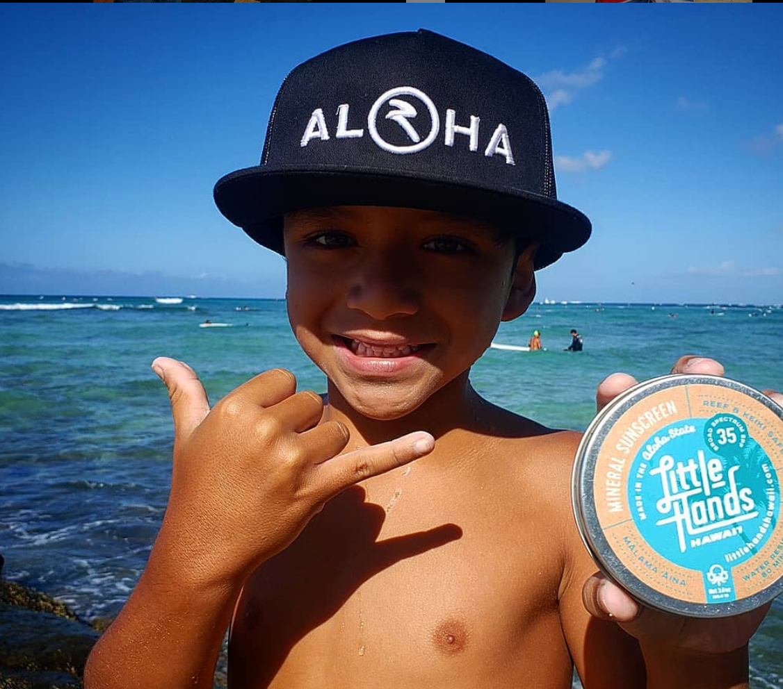 Kingston holding up Little Hands Hawaii mineral sunscreen